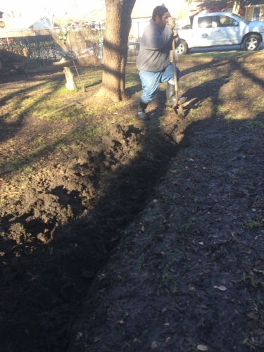 A worker installs a drainage system as part of landscape drainage services in Fort Worth